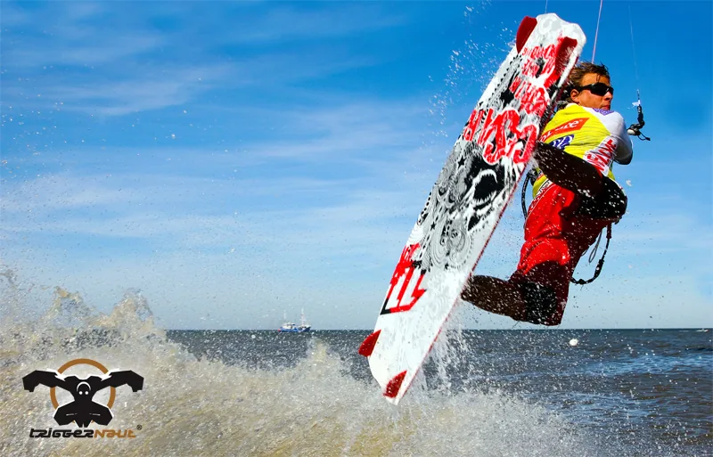 Actionsport-Motiv der Marke TRIGGERNAUT: Kiteboarder im Sprung über dem Meer, unten links das TRIGGERNAUT-Logo